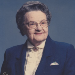Woman smiling in a blazer with glasses