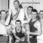 Five male basketball players holding a man up on their shoulders, smiling